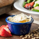 A blue Carlisle ramekin filled with white food next to a salad.
