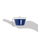 A hand holding a Carlisle cobalt blue melamine ramekin with a measuring tape to show its height.
