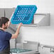 A man using a Regency wall mounted shelf in a kitchen to hold a blue container.