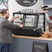 A man opening a bakery display case on a counter.