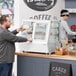 A man taking a piece of food from a white Avantco countertop bakery display case.