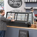 A man and woman standing at a countertop bakery display case.