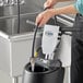 A person using a Lavex rotary floor machine with a solution tank to clean a floor in a professional kitchen.