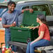 A man and woman sitting on the back of a truck with a CaterGator Hunter Green cooler.