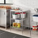 A Regency metal shelving unit in a professional kitchen with food items on it.