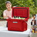 A woman putting bottles in a red CaterGator outdoor cooler.