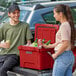 A man and woman standing next to a red CaterGator cooler filled with ice and beer bottles.