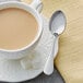 A cup of coffee with an Acopa Vittoria stainless steel demitasse spoon on a saucer.