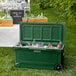 A CaterGator hunter green outdoor cooler filled with ice and drinks on a table.