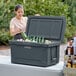 A woman putting bottles into a CaterGator outdoor cooler.