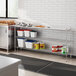 A Regency metal shelving unit on a stainless steel counter in a professional kitchen.