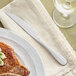 A plate with a steak and an Acopa Brigitte stainless steel steak knife on it.