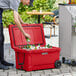 A man putting a can of beer into a red CaterGator outdoor cooler.