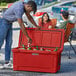 A man wearing a hat opening a CaterGator red cooler filled with beer bottles.