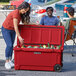 A woman putting a can into a red CaterGator outdoor cooler.