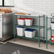 A kitchen with a silver refrigerator and a green Regency wire shelf.