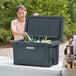 A woman putting bottles of beer into a CaterGator outdoor cooler.