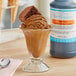 A glass of brown liquid with brown ice cream in it on a counter.