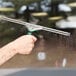 A hand holding a Unger ErgoTec window squeegee to a window.