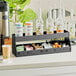 A black ServSense countertop condiment organizer holding condiments and bottles.