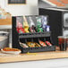 A black ServSense countertop condiment organizer on a black counter.