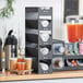 A ServSense black countertop lid organizer holding clear lids over white paper cups.