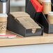 A black ServSense countertop coffee sleeve organizer holding coffee cups.