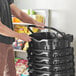 A man holding a stack of black Regency shopping baskets.