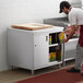 A man in a black apron putting food in a Regency enclosed base table cabinet.