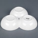 A CAC white three bowl tasting dish sitting on a gray surface.