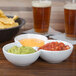 A CAC white china bowl filled with guacamole on a table with bowls of chips and salsa.