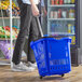 A person pushing a blue shopping basket with wheels.