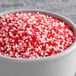 A bowl of red and white nonpareil sprinkles.