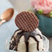 A close-up of a Daelmans chocolate mini stroopwafel on a table with ice cream.