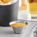 An American Metalcraft stainless steel sauce cup with fries and yellow liquid.