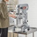 A man using an Avantco planetary stand mixer to mix flour in a bowl.