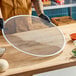 A large, round, heavy-duty expanded aluminum pizza screen.