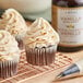 A white cupcake with vanilla frosting on a cooling rack.