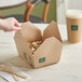 A hand taking New Roots Kraft PLA-Lined take-out food from a paper box.