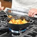 A person cooking food in a Chasseur enameled cast iron pan on a stove.