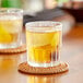 A table with two Duralex Jazz Old Fashioned glasses of liquid on coasters.