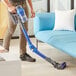 a person holding a blue and silver vacuum cleaner