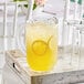 A Carlisle clear polycarbonate pitcher of lemonade on a tray with glasses.