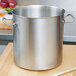A large silver pot on a wood surface.