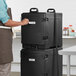 A man in an apron putting a white adhesive label on a stack of black CaterGator containers.