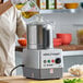 A woman pouring liquid into a Robot Coupe food processor.