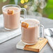 A glass mug of UPOURIA Salted Caramel Hot Chocolate with a caramel on top.
