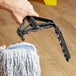 A hand using a Lavex yellow metal mop handle to mop a floor.