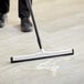 A person cleaning a floor with a Lavex double neoprene foam floor squeegee.