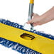 A hand using a Lavex swivel snap wire dust mop frame.